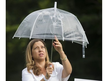 A participant adjusts lights in her umbrella as she sets the table at the 7th Annual Le Dîner en Blanc  at the VanDusen Botanical Garden in Vancouver on Thursday.