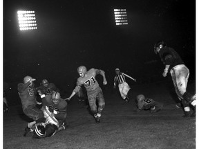 B.C. Lions Neil Ferris (71) and Bob Levenhagen (54) in action against the Winnipeg Blue Bombers on Aug. 28, 1954, the first Lions regular season game at Empire Stadium. Brian Kent/Vancouver Sun.