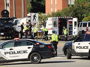 Police officers and paramedics survey the area of a shooting in Fredericton, N.B. on Friday, August 10, 2018.