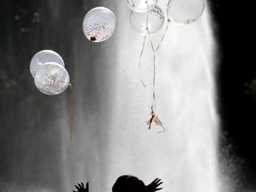 FILE- In this Oct. 5, 2017, file photo Annette Antwi, of Newark, N.J., releases balloons while celebrating her birthday in front of a fountain at Branch Brook Park in Newark, N.J. As companies vow to banish plastic straws, there are signs balloons are among the products getting more scrutiny.