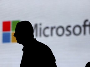 FILE - In this Nov. 7, 2017, file photo, a man is silhouetted as he walks in front of Microsoft logo at an event in New Delhi, India.