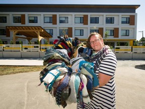 Paula Lindner, owner of Baaad Anna's Yarn Store in Vancouver, holds donated socks in front of a modular housing building on Kaslo Street.