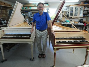Craig Tomlinson in his backyard workshop with the two French harpsichords he's in the process of building.