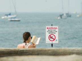 A woman reads a book Tuesday at Sunset Beach in Vancouver. No-swimming advisories were lifted Tuesday afternoon at Sunset and nearby English Bay Beach but a similar warning remains in effect for Jericho Beach.