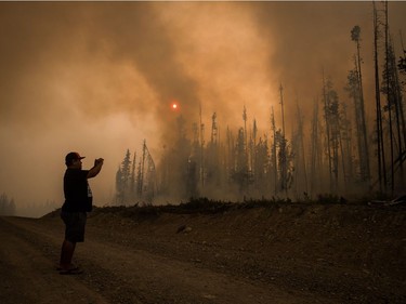 Verne Tom photographs a wildfire burning along a logging road approximately 20km southwest of Fort St. James, B.C., on Wednesday, August 15, 2018. The British Columbia government has declared a provincial state of emergency to support the response to the more than 500 wildfires burning across the province.