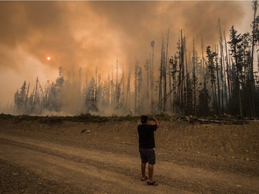 Verne Tom photographs a wildfire burning approximately 20km southwest of Fort St. James, B.C., on Wednesday, August 15, 2018. The British Columbia government has declared a provincial state of emergency to support the response to the more than 500 wildfires burning across the province.