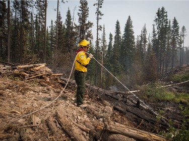 Firefighter Christian Garcia, of Mexico, puts out hot spots in an area burned by the Shovel Lake wildfire near Endako, B.C., on Thursday, August 16, 2018. The Shovel Lake wildfire is more than 680 square kilometres in size and is the largest of the more than 500 fires burning across the province.