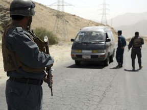 Afghan police officers search a vehicle at a checkpoint on the Ghazni highway, in Maidan Shar, west of Kabul, Afghanistan, Monday, Aug. 13, 2018.
