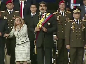 In this still from a video provided by Venezolana de Television, President Nicolas Maduro, centre, delivers his speech as his wife Cilia Flores winces and looks up after being startled by and explosion, in Caracas, Venezuela, Saturday, Aug. 4, 2018.