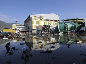 People survey the damage of a shopping mall following earthquakes and tsunami in Palu, Central Sulawesi, Indonesia, Sunday, Sept. 30, 2018.  Rescuers are scrambling to try to find trapped victims in collapsed buildings where voices could be heard screaming for help after a massive earthquake that spawned a deadly tsunami in Indonesia two days ago.