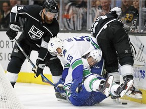 Vancouver Canucks' Alex Biega (55) and Nikolay Goldobin (77) collide as they battle Los Angeles Kings' Jake Muzzin (6) and Alec Martinez in the second period.