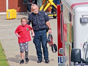A B.C. Ambulance Service paramedic comforts a Dufferin elementary student after 135 students were stung by wasps during their annual Terry Fox run in Kamloops. Students ran across a ground nest on a trail near the school.