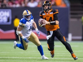 B.C. Lions quarterback Travis Lulay, right, is chased by Winnipeg Blue Bombers' Adam Bighill before completing a pass to Bryan Burnham during the second half of a CFL football game in Vancouver, on Saturday July 14, 2018.