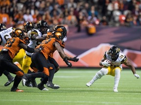 Hamilton Tiger-Cats' John White IV (28) stops after seeing B.C. Lions' Ivan McLennan (98) and Davon Coleman, back centre, coming towards him during the second half of a CFL football game in Vancouver, on Saturday September 22, 2018.