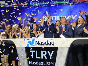 FILE- In this July 19, 2018, file photo Brendan Kennedy, third from right in front, CEO and founder of British Columbia-based Tilray Inc., a major Canadian marijuana grower, leads cheers as confetti falls to celebrate his company's IPO (TLRY) at Nasdaq in New York.