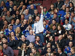 A fan holds up a game puck during the NHL game between the Vancouver Canucks and the Los Angeles Kings in January 2018.