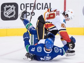 Calgary Flames' Dillon Dube (59) checks Vancouver Canucks' Kole Lind (78) during the second period on Wednesday night.