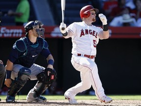 Los Angeles Angels' Kole Calhoun, right, hits a solo home run with Seattle Mariners catcher Mike Zunino watching during the seventh inning of a baseball game in Anaheim, Calif., Sunday, Sept. 16, 2018.