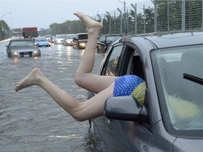 A woman gets gets back in her car in flood water on Lakeshore West during a storm in Toronto on Monday, July 8, 2013.