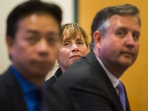 Shauna Sylvester (centre) listens as she's seen between Ken Sim (left) and Kennedy Stewart (right) during at town hall involving six candidates for mayor of Vancouver.