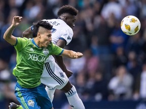 Seattle Sounders' Raul Ruidiaz, front, and Vancouver Whitecaps' Alphonso Davies vie for the ball during the first half of an MLS soccer game in Vancouver, on Saturday September 15, 2018.