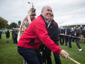 B.C. Premier John Horgan, front, and Hereditary Chief David Mungo Knox, back left, of the Kwakiutl First Nation, help raise a replica of a Haida totem pole on the traditional territory of the Semiahmoo First Nation, at the Douglas-Peace Arch border crossing, in Surrey, B.C., on Friday September 21, 2018.