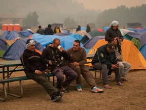 Firefighters from Mexico sit together at a camp where wildfire firefighters and staff are staying at an outdoor sports field, in Fraser Lake, B.C., on Wednesday August 22, 2018. A state of emergency was declared by the British Columbia government as hundreds of fires burn across the province.