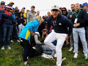 U.S. golfer Brooks Koepka, right, reacts next to an injured spectator who fell during the fourball match on the first day of the 42nd Ryder Cup at Le Golf National Course at Saint-Quentin-en-Yvelines, south-west of Paris on September 28, 2018.