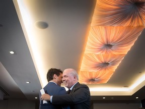 Prime Minister Justin Trudeau, left, and B.C. Premier John Horgan shake hands and embrace during an LNG Canada news conference in Vancouver on Tuesday, Oct. 2. LNG Canada announced that its joint venture participants Shell, PETRONAS, PetroChina, Mitsubishi Corporation and KOGAS made a final investment decision to build the LNG Canada export facility in Kitimat.