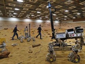 In this Thursday, March 27, 2014 file photo, personnel walk on the 'Mars Yard Test Area', a testing ground where robotic vehicles of the European Space Agency's ExoMars program scheduled for 2018, are tested in Stevenage, England. The U.K. Space Agency is looking for a catchy name for the ExoMars Rover being developed for use in a mission set for 2020. The agency launched a competition Friday, July 20, 2018 to find the best name for the rover, a key U.K. contribution to the European Space Agency’s Mars voyage.