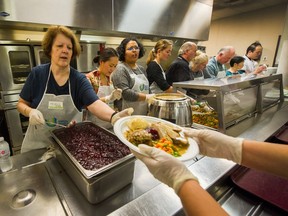 Volunteer Michelle Renaud puts on the finishing touches (cranberry sauce) and hands plates to servers as thousands attend Thanksgiving dinner at Union Gospel Mission in Vancouver.