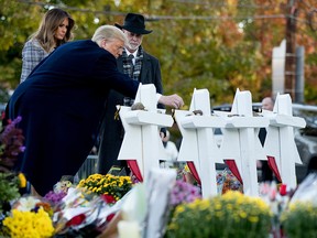 U.S. President Donald Trump, accompanied by first lady Melania Trump, left, and Tree of Life Rabbi Jeffrey Myers, right, places a stone from the White House at a memorial for those killed at the Tree of Life Synagogue in Pittsburgh, Tuesday, Oct. 30, 2018.