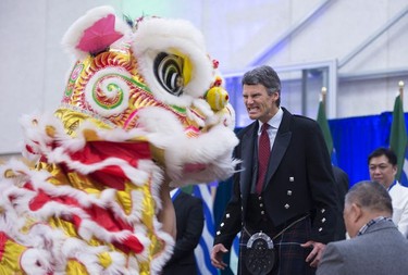 Vancouver Mayor Gregor Robertson makes a face at the Chinese Lion during a dance after being sworn in during a ceremony in Vancouver, Dec. 8, 2014.