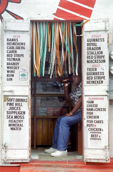 A local enjoys  a beer inside a Barbados  Rum Shop showing the various drinks for sale.