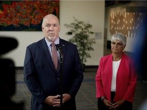 MLA Carole James looks on as B.C. Premier John Horgan speaks to media following a meeting with federal ministers at the Vancouver Island Conference Centre during day two of the Liberal cabinet retreat in Nanaimo, B.C., on Wednesday, August 22, 2018.