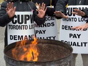 Striking Canada Post workers keep their hands warm as they picket at the South Central sorting facility in Toronto on Tuesday, November 13, 2018.