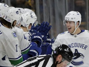 Vancouver Canucks players on the bench reach out to defenseman Ben Hutton to celebrate his goal during the second period.