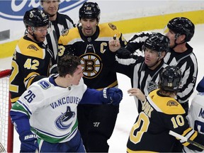 Referees separate Canuck Antoine Roussel and Bruin David Backes.