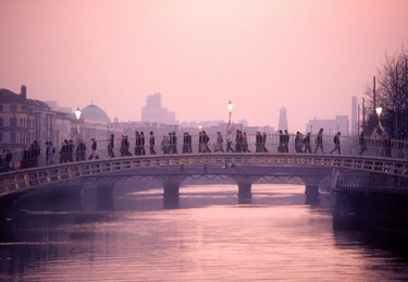 At twilight, people cross a footbridge over the River Liffey in Dublin city.