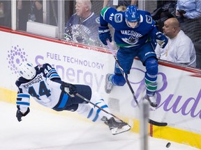 Josh Morrissey and Elias Pettersson collide during the second period Monday.