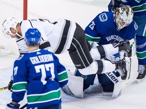 Los Angeles Kings' Jeff Carter, back left, trips over Vancouver Canucks goalie Jacob Markstrom, of Sweden, as Nikolay Goldobin (77), of Russia, watches during the second period of an NHL hockey game in Vancouver, on Tuesday November 27, 2018.