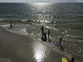 A family ventures into the water at Naples Beach as the sun begins to dip in the sky.