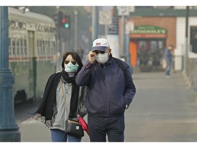 FILE - In this Nov. 16, 2018 file photo, a couple wears masks while walking at Fisherman's Wharf through smoke and haze from wildfires in San Francisco. From air pollution triggered by wildfires that caused people in Northern California to don breathing masks to increased asthma attacks that send children to the hospital, medical experts said climate change is hurting people's bodies.