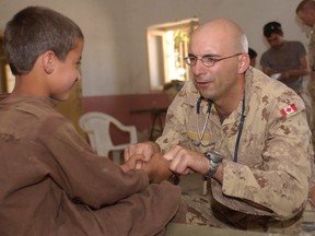 Then Master Cpl. Eric Demers, a physician assistant, jokingly grimaces as he asks a young boy to squeeze his fingers as part of an examination during a tour of duty in Afghanistan in 2005. Demers, who was able to work as a physician assistant in B.C. while with the Canadian Forces, cannot as a civilian because B.C. law does not recognize the profession.