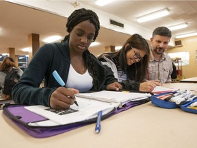 Steve Sorrenti (right), a youth worker at Sir Charles Tupper Secondary School, looks over Antonia Gilfoyle (left) and Kimberly Villanueva while attending his homework club. The school is asking The Vancouver Sun Children's Fund Adopt-a-School for money to help feed hungry teens who are coming to the school's homework club for help and support.