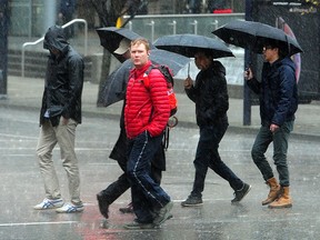 Pedestrians brave the rain as Environment Canada issues a heavy rain and high wind weathern warning, in downtown Vancouver, November 26, 2018.