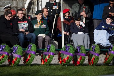 Royal Canadian Air Force veteran Colleen de Serres, second right, 86, who flew the Tiger Moth single engine aircraft in France during the Korean War, wipes away a tear after placing a white rose on the cenotaph at Victory Square during a Remembrance Day ceremony in Vancouver, on Sunday November 11, 2018. Her great-uncle is Canadian aviation pioneer Douglas McCurdy. Seated at right is Second World War veteran Howard Costain, 98.