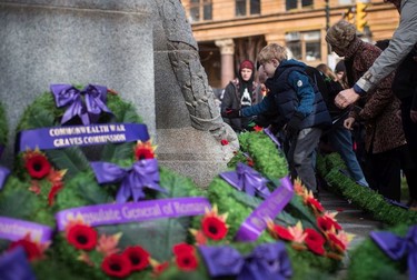A young boy places his poppy on a wreath at the Victory Square Cenotaph after a Remembrance Day ceremony in Vancouver, on Sunday, November 11, 2018.