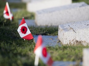 Poppies and Canadian flags are seen at the graves of soldiers at Mountain View Cemetery in Vancouver, Saturday, Nov. 10, 2018. A newly installed headstone honours an Alaskan family killed in a shipwreck just as WWI neared its end.