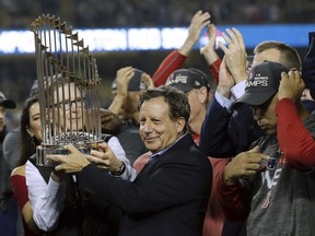 Boston Red Sox owner John Henry, partially hidden behind the Commissioner’s Trophy, and club chairman Tom Werner are on top of the world after accepting the trophy for winning the World Series last Sunday at Dodgers Stadium in Los Angeles.